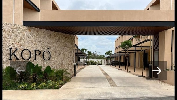 A modern building entrance with a stone wall and the name "KOPÓ" displayed. - New & beautiful apartment (GF) with private pool (Mérida)