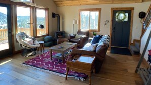 A cozy living room with a fireplace, leather furniture, and large windows offering mountain views.