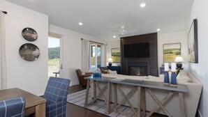 Een moderne woonkamer met een open haard, een bank, een salontafel en een eethoek met een tafel en stoelen.