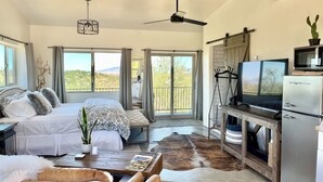 Una habitación amplia con una cama, una mesita de centro, un televisor y un refrigerador.