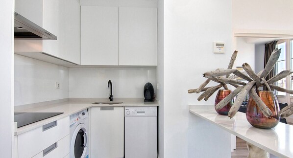 A modern kitchen with a dishwasher, a coffee machine, and a decorative vase.