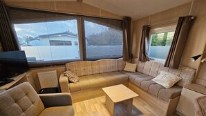 Ein kleiner Wohnraum mit Sofa, Tisch, Fernseher und Heizkörper.