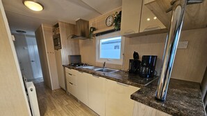 Eine Küche mit Holzausbau, einer Granitabdeckung, einem Herd, einer Spüle und einer Kaffeemaschine.