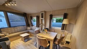 Ein kompakter, gut beleuchteter Wohnbereich mit einer Couch, einem Esstisch und einer kleinen Küchenzeile.