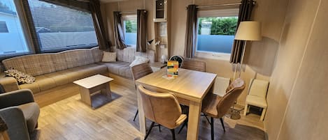 A compact, well-lit living area with a sofa, a dining table, and a small kitchen area.
