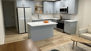 A modern kitchen with grey cabinets, a white countertop, and a central island. - Sunshine Swimmers Casita, 206 (Englewood)