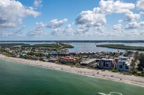 An aerial view of a coastal town with beachfront properties, a marina, and a clear sky. - Sunshine Swimmers Casita, 206 (Englewood)