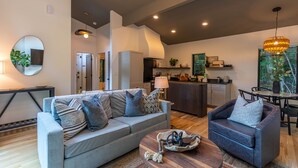 Ein modernes Wohnzimmer mit grauem Sofa, einem Holztisch und einem Essbereich mit Tisch und Stühlen.