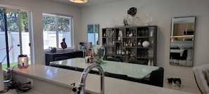 A modern kitchen with a central island, a built-in wine rack, and a dining area with a glass table.