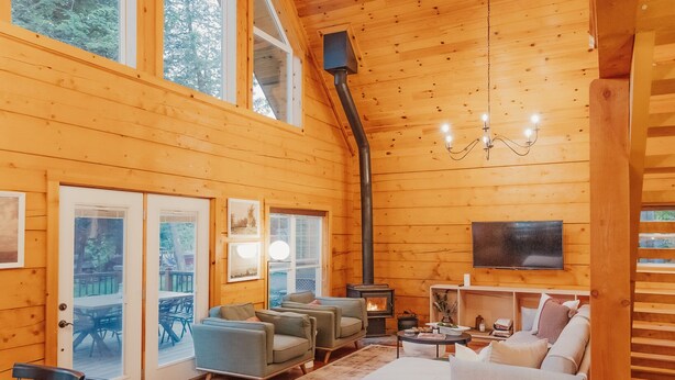 A spacious wooden cabin with a dining area, sofas, and a fireplace. - Boutique All Wood Cottage in the Woods (Lanark)