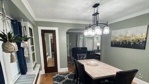 A dining area with a long table, chairs, a patterned rug, and a chandelier. - Downstairs Unit near National Park + Downtown Cleveland (Cleveland)