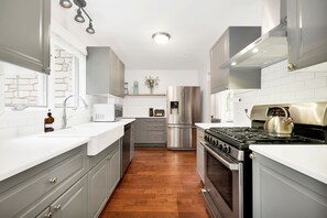 Una cocina moderna con armarios grises, un refrigerador de acero inoxidable, una estufa y un lavamanos.
