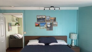 Une chambre à coucher avec un lit, une table de chevet, une lampe et un mur orné de tableaux.