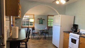 Une cuisine compacte équipée d’un réfrigérateur, d’une cuisinière et d’un coin repas avec des chaises et une table.