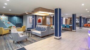 A modern lobby with seating areas, a reception desk, and a large wall mural.