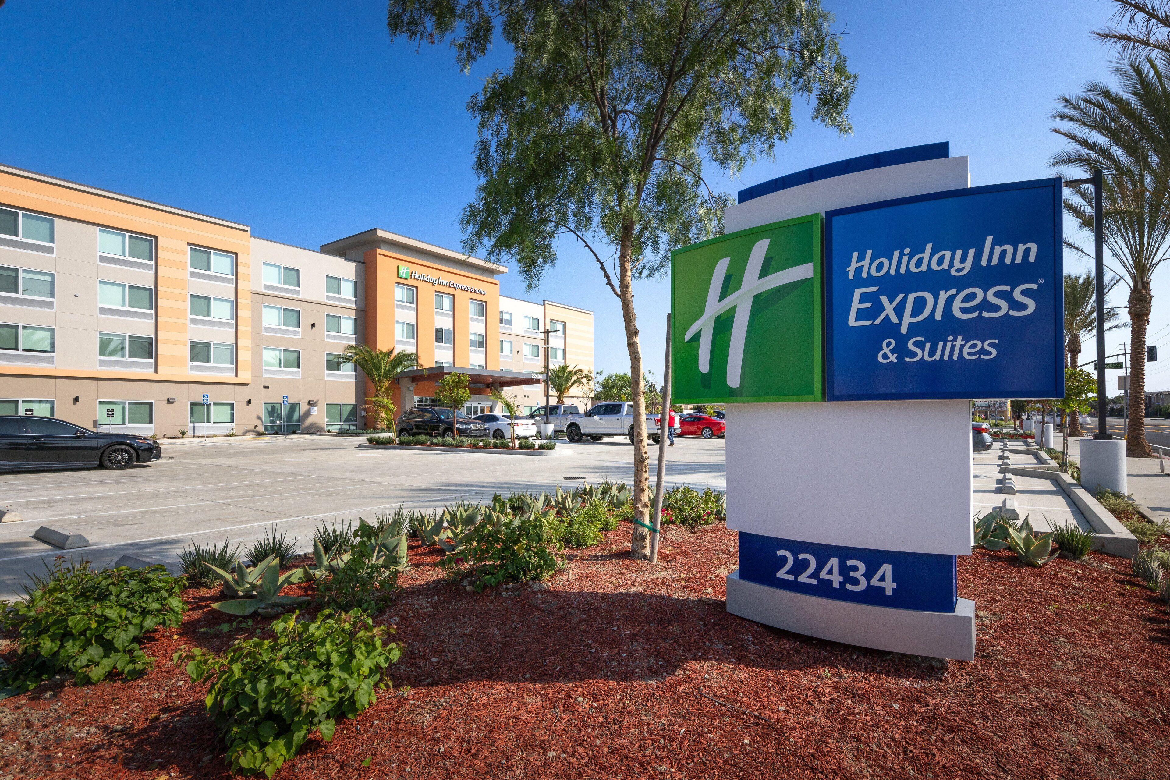 A Holiday Inn Express & Suites sign with the number 22434, surrounded by landscaped areas and a parking lot with vehicles.
