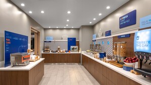 A modern breakfast area with a coffee machine, cereal display, and a juice dispenser.