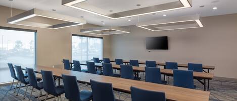 A conference room with a long table, blue chairs, and modern lighting fixtures.