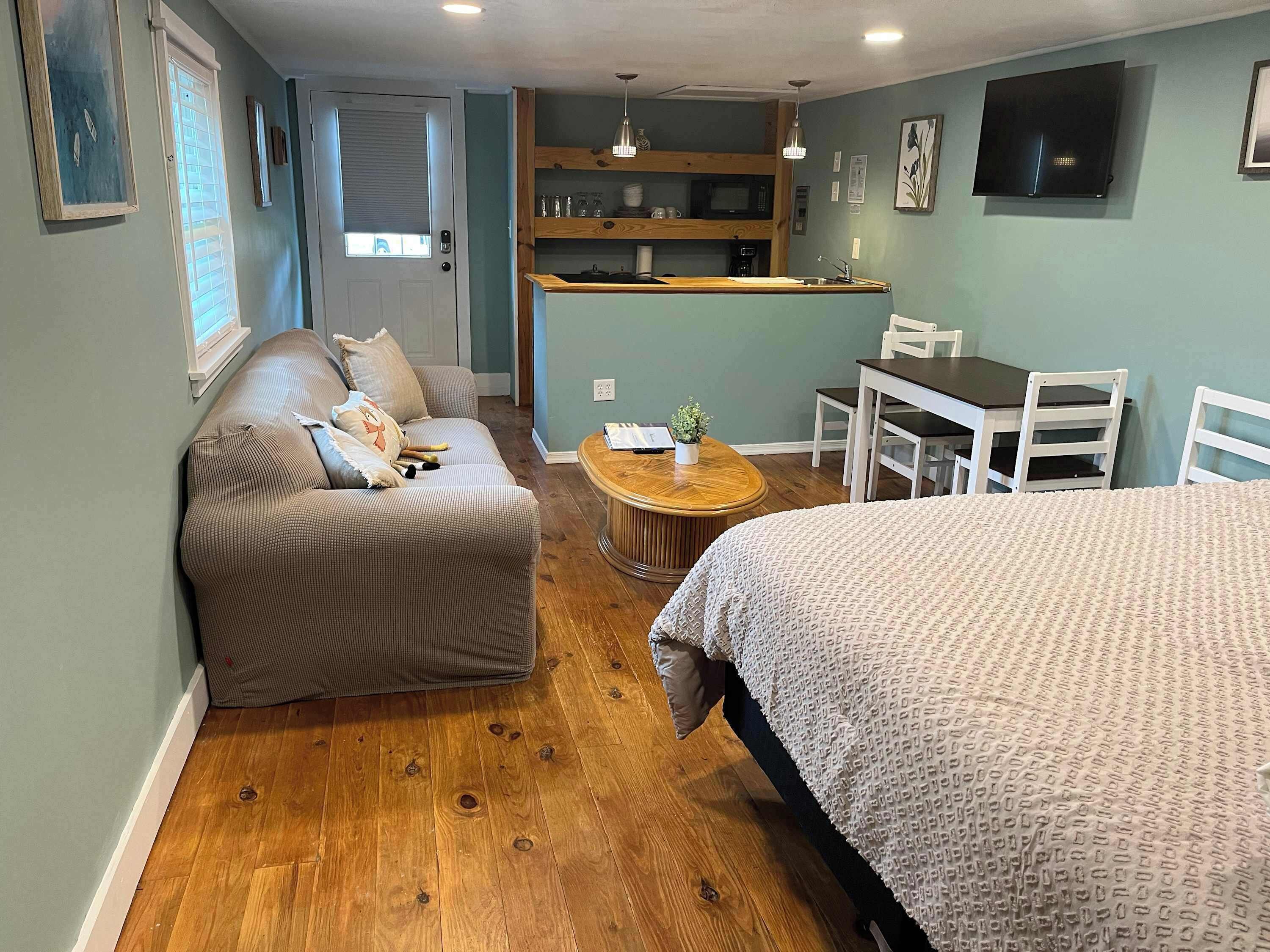 A cozy room with a sofa, a bed, a dining table, and a kitchen area.