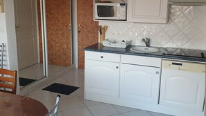 A compact kitchen with white cabinets, a microwave, a sink, and a dishwasher. - The Blue of 0pale (Cucq)
