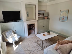 Un salon avec une cheminée, un téléviseur, un canapé, une table basse et un fauteuil.