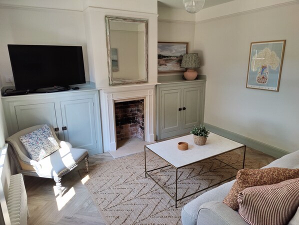 A living room with a fireplace, a television, a sofa, a coffee table, and a chair.