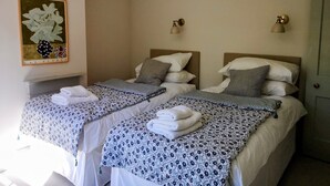 Ein Hotelzimmer mit zwei Betten, jeweils mit gemusterten Bettbezügen und Kissen, einem Wandbild und je einer Nachttischlampe.
