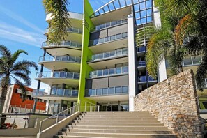 Un hotel de varios pisos con una escalera central, balcones y una pared de piedra.