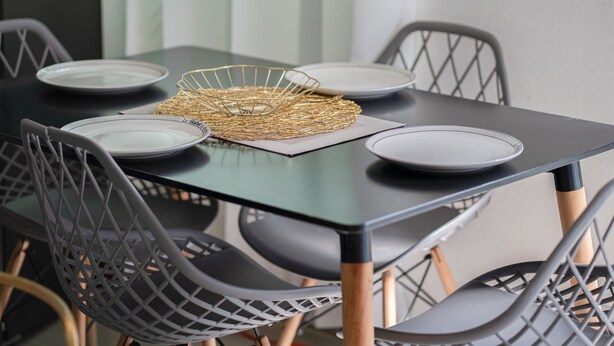 Una mesa de comedor con cuatro platos, una cesta de alambre dorado y un mantel individual.