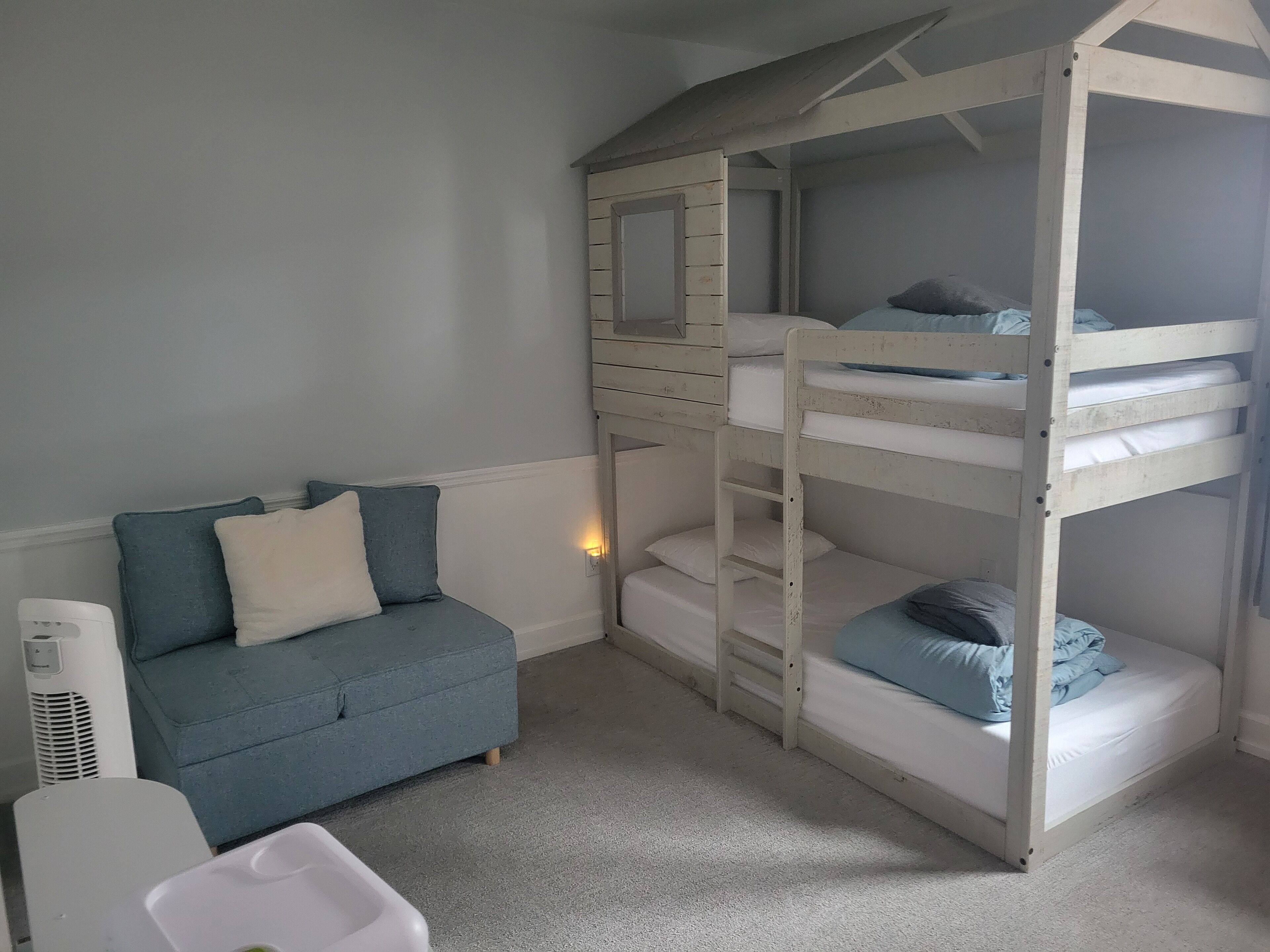 Una habitación con literas, un sofá azul y un calentador blanco.