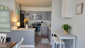 A modern kitchen with grey cabinets, a central island with stools, a microwave, oven, and a sink. - Bright, Modern Park Forest Home, 2.5m to Penn State! Breakfast included.  (State College)