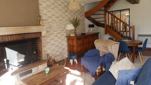 A living room with a fireplace, wooden furniture, a staircase, and a dining area. - Renovated 150-year-old building, close to Chateau de Menou. (Menou)