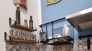 A kitchen with a sink, a decorative clock, and a shelf with spices. - Typical Sicilian cottage equipped with all comforts at the centr (Palermo)