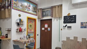 A room with a wooden door, a small table with chairs, a wall-mounted shelf, and a red sofa. - Typical Sicilian cottage equipped with all comforts at the centr (Palermo)
