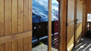 A wooden cabin with a sliding glass door leading to a deck. - Chalet 8 pers - 50m from the slopes (Valmeinier)