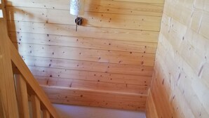 A wooden staircase with a handrail, leading to a landing with a white wall and a small white object on the wall. - Chalet 8 pers - 50m from the slopes (Valmeinier)