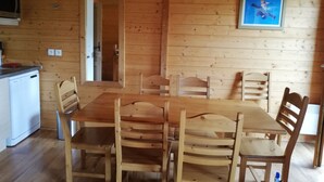 A wooden interior with a dining table and chairs, a kitchen area with a dishwasher, and a framed picture on the wall. - Chalet 8 pers - 50m from the slopes (Valmeinier)