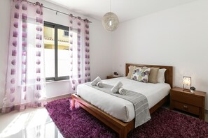 Une chambre à coucher avec un lit en bois, une table de chevet avec une lampe et un tapis violet.