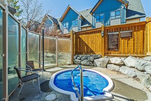 A backyard with a hot tub, a wooden fence, and a house in the background.