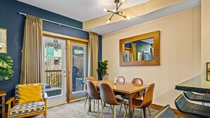 A dining area with a wooden table, four chairs, and a large mirror on the wall. - Family & Group Oasis: Hot Tub, AC, Fireplace, 2 Patios, Walk to Food & Shops (Canmore)