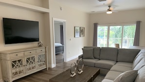 A living room with a sectional sofa, a coffee table, a TV, and a cabinet. - Coastal Tranquility in Quiet, Gated Community (Rotonda West)