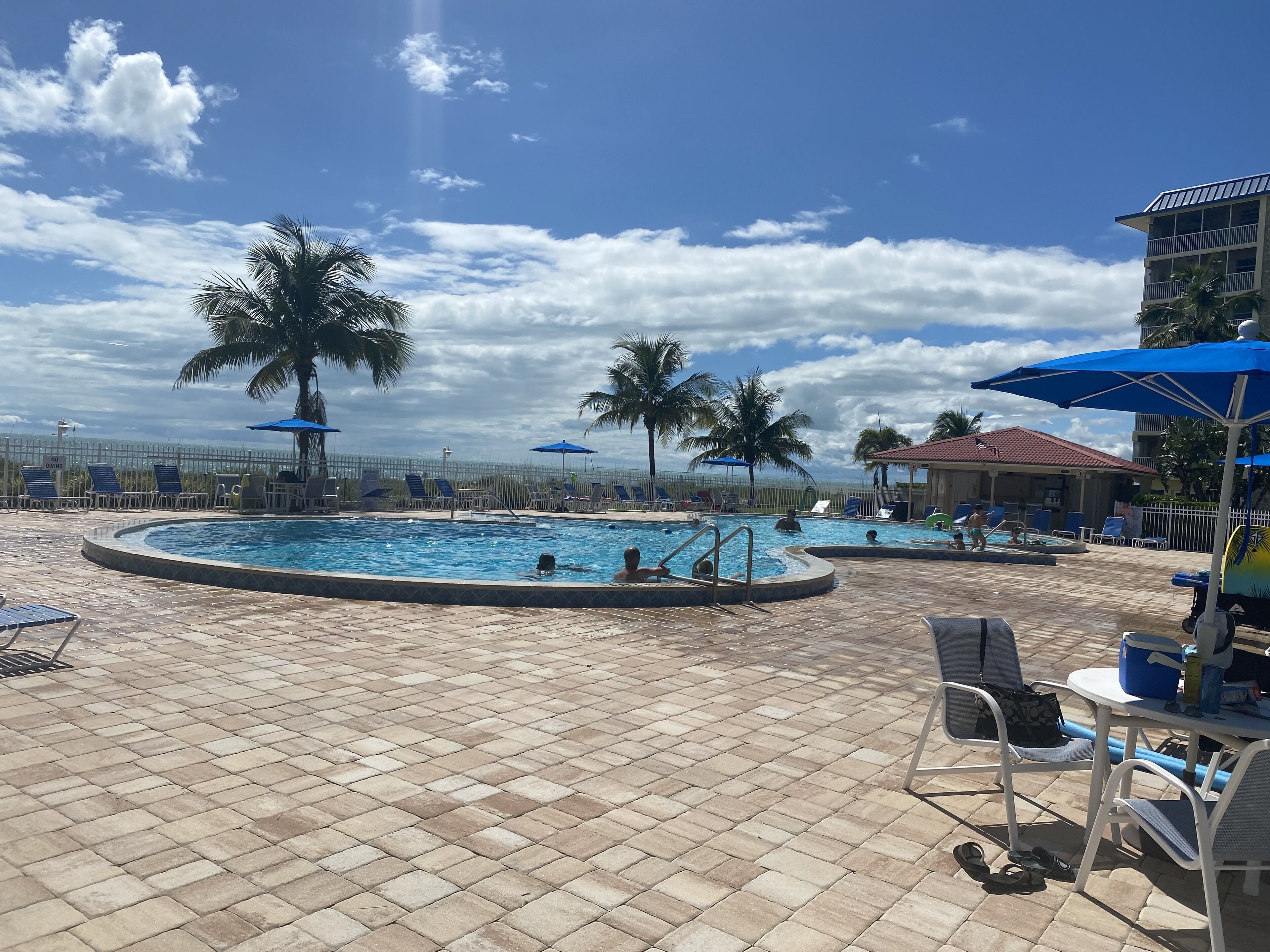 Un área de piscina con varias piscinas, sillas de descanso y sombrillas.
