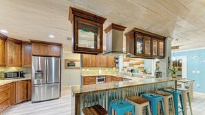 Una cocina moderna con armarios de madera, electrodomésticos de acero inoxidable y una isla central con taburetes de bar.