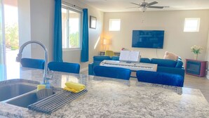 A modern kitchen with a granite countertop, a sink, and a dining area with blue chairs and a blue sofa. - Modern 3 BD House in Cottonwood Downtown, 20 mins to Sedona.  (Cottonwood)
