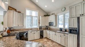 A spacious kitchen with white cabinets, granite countertops, and a large island. - Private 5 Bedroom East Vail Getaway by Gorecreek Rentals (Vail)