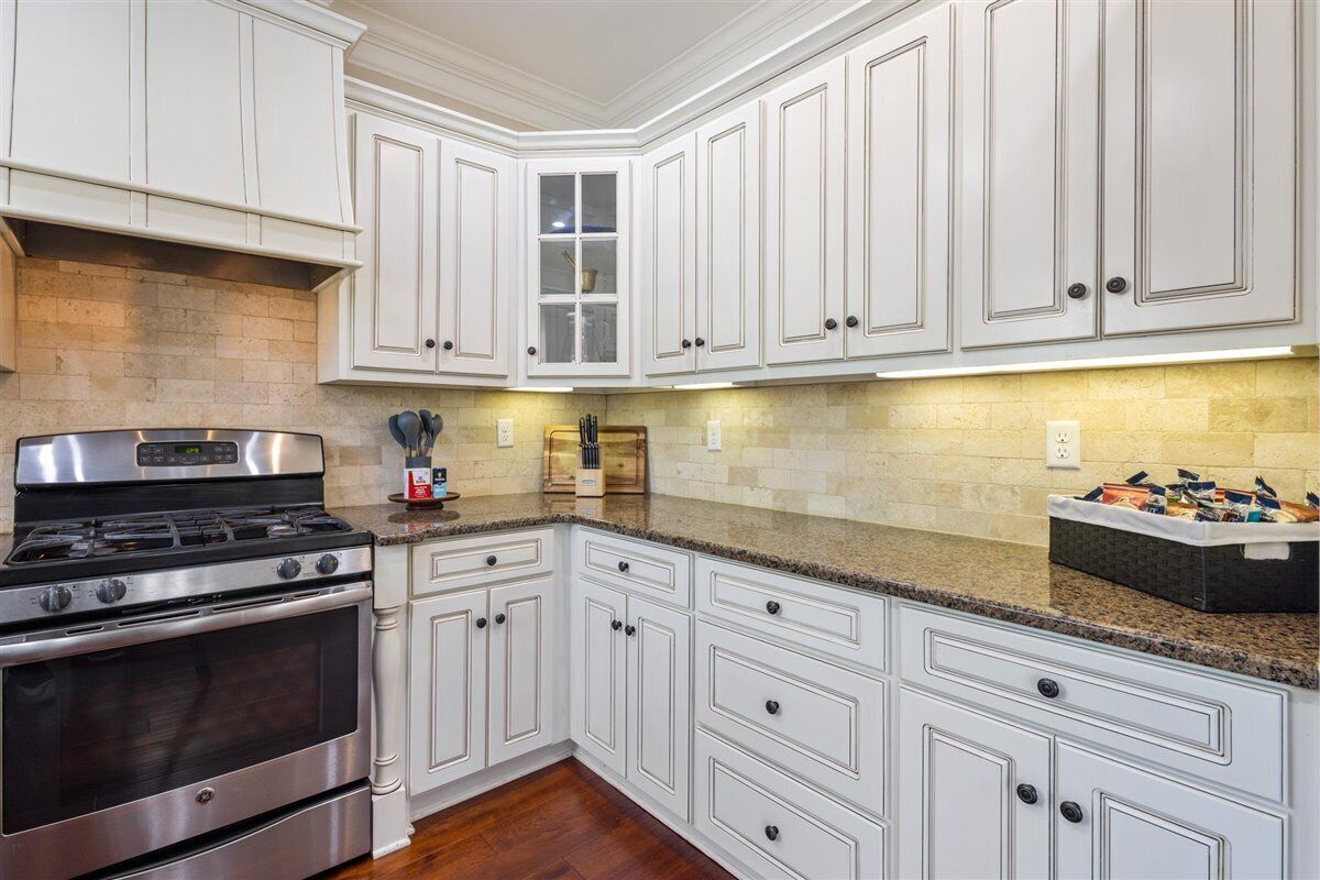 A kitchen with white cabinetry, a stainless steel stove, and granite countertops.