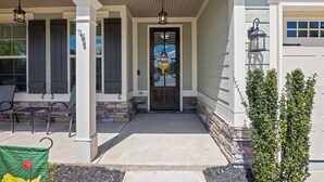 A house with a porch, a door with a welcome sign, and a small tree. - Masters Golf Rental, Overlooks Course (Evans)