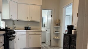 A kitchen with white cabinets, a black stove, and a wooden floor.
