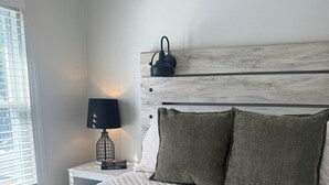 A neatly made bed with a quilted white duvet, a dark green knitted throw, and two matching pillows.