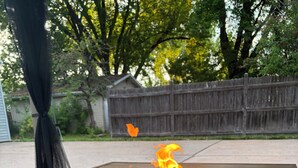 A square outdoor fire feature with a black base and a wooden top.